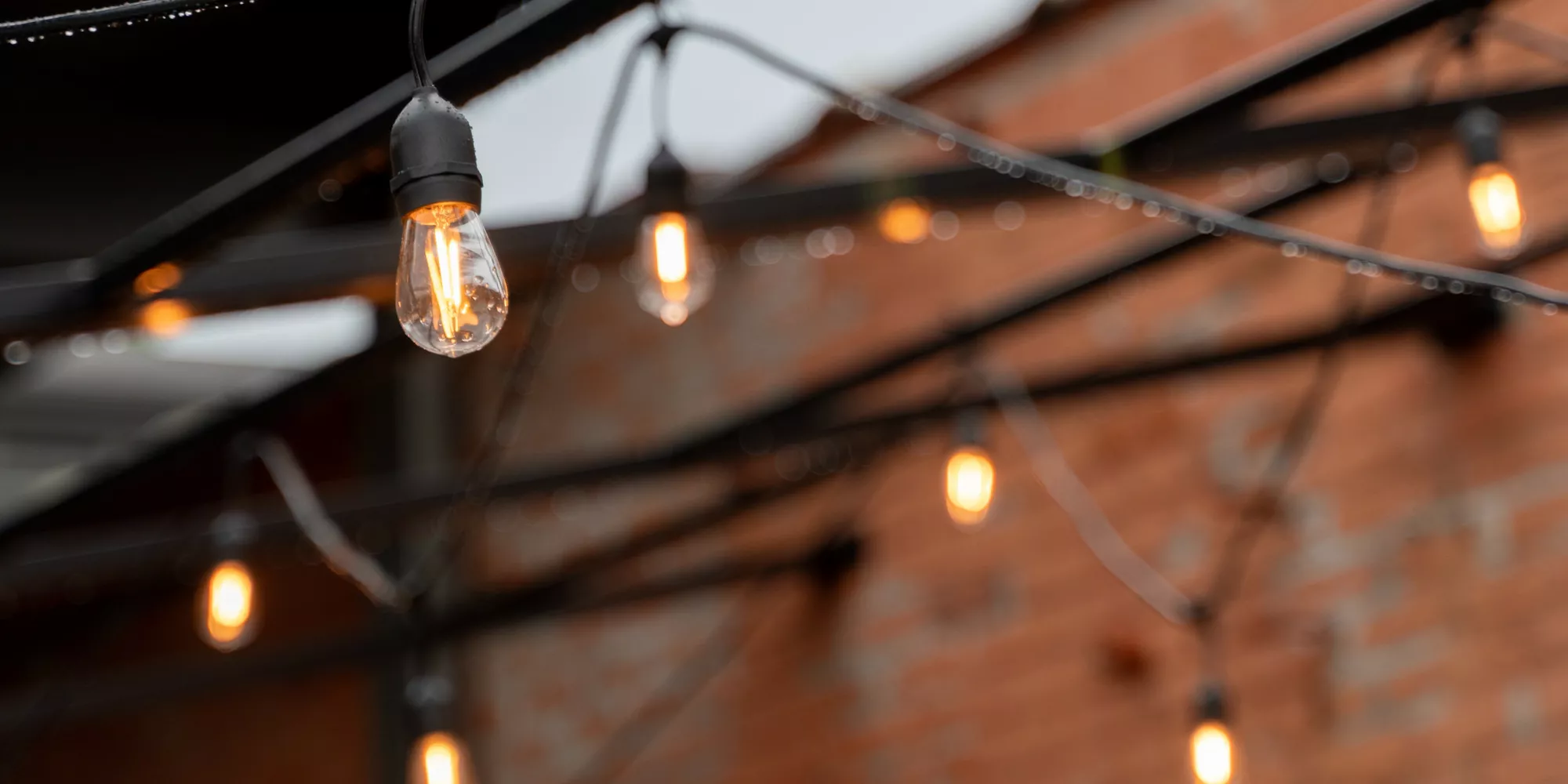 Warm festoon lighting strung across a brick courtyard