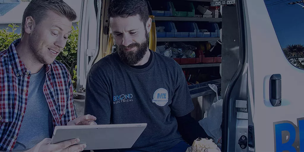 A Beyond Electrical electrician talking a customer through the job beside the van